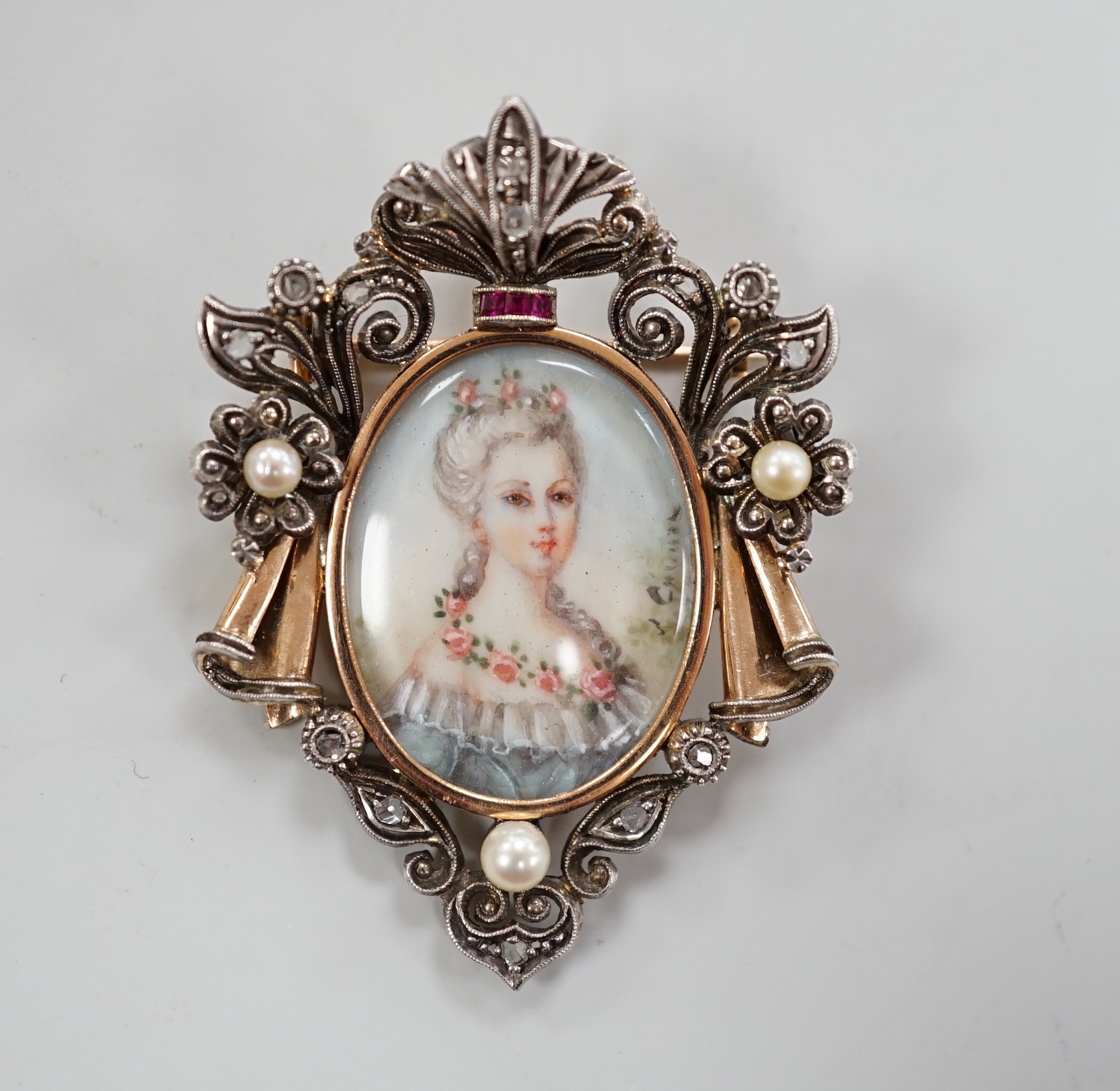 A late 19th/early 20th century continental yellow metal, seed pearl, ruby and diamond mounted pendant brooch, with inset oval miniature watercolour of a lady, indistinctly signed, 47mm, gross weight 10 grams., CITES Subm